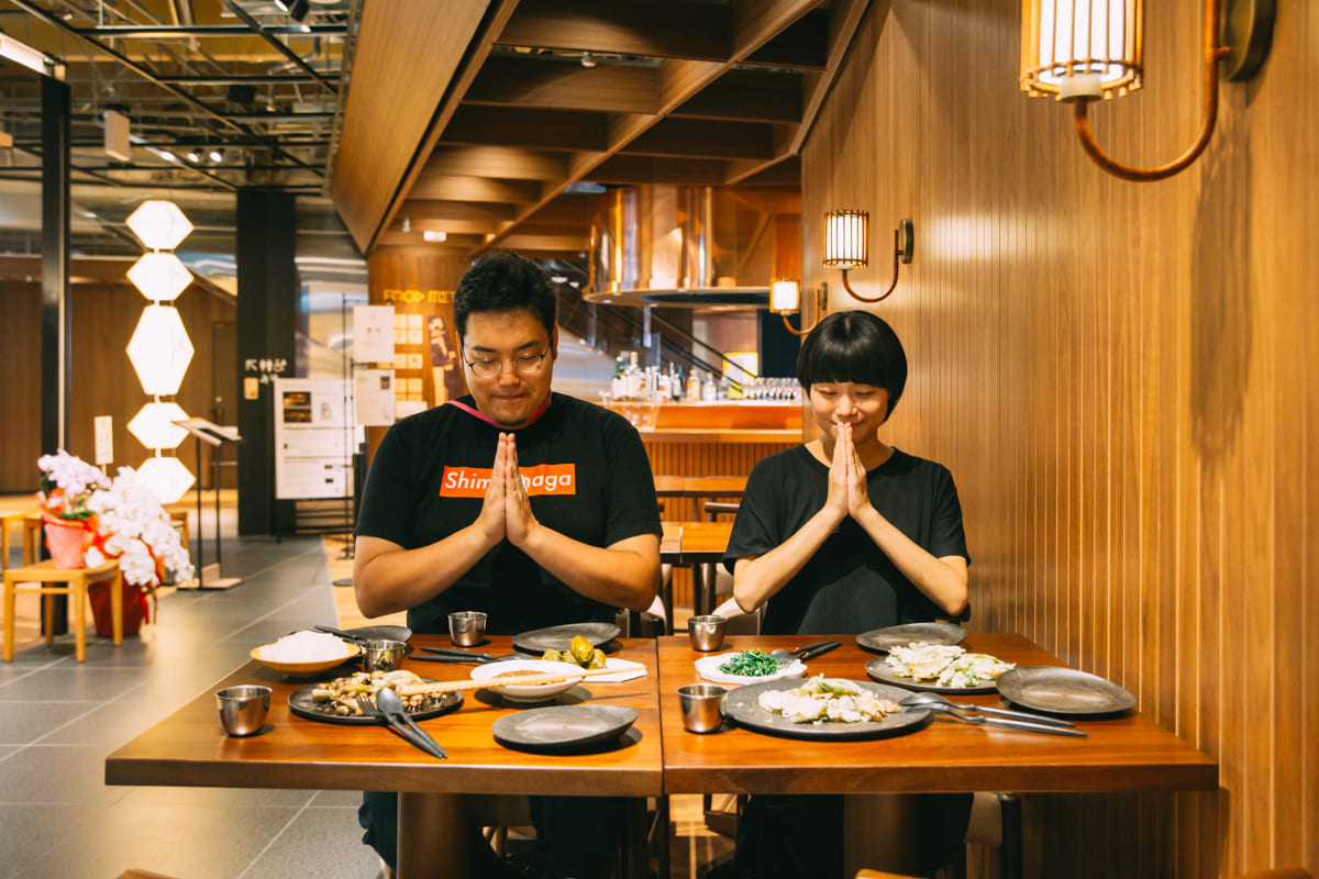 料理を前に手を合わせる茸本さんとスタッフ